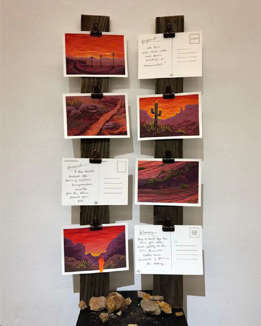 A series of postcards with paintings of pink and purple desert landscapes. Postcards have poems written on the other side.