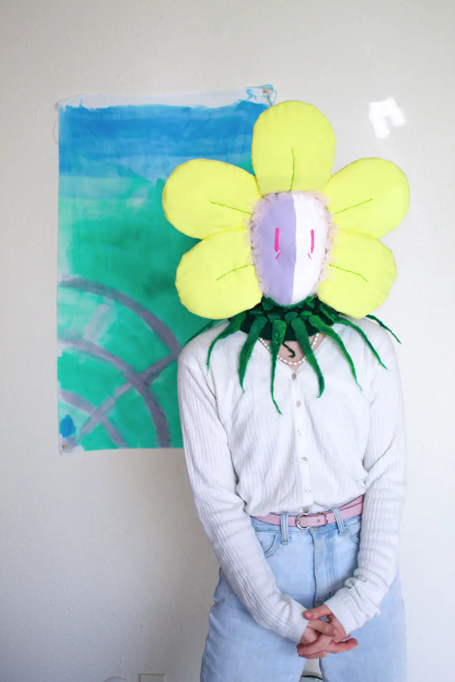 A person wearing a felt-created flower head. The flower has pale yellow petals.